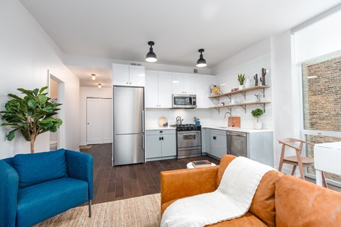 A modern kitchen with a blue chair and orange couch.