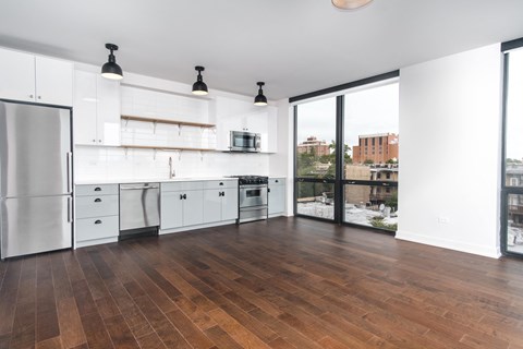 A kitchen with white cabinets and a wooden floor.