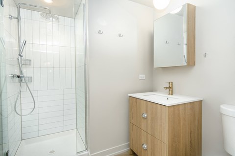 A white sink with a gold faucet is on a wooden cabinet in a bathroom.