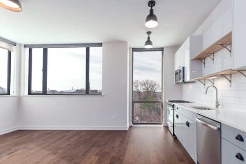 A kitchen with white cabinets and a wooden floor.