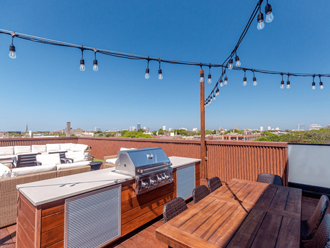 A rooftop patio with a grill and dining table.