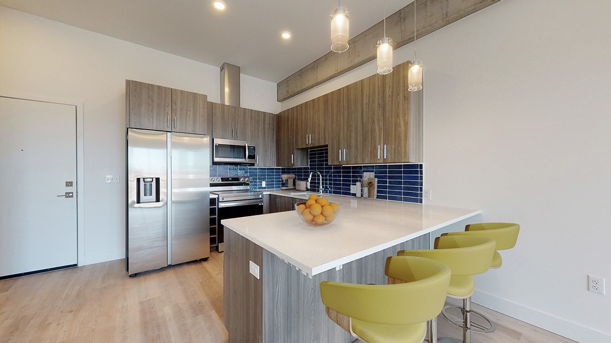 A kitchen with a white counter top and yellow chairs.