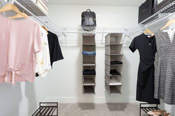 a walk in closet with a rack of clothes and shelves and a rack with shelves