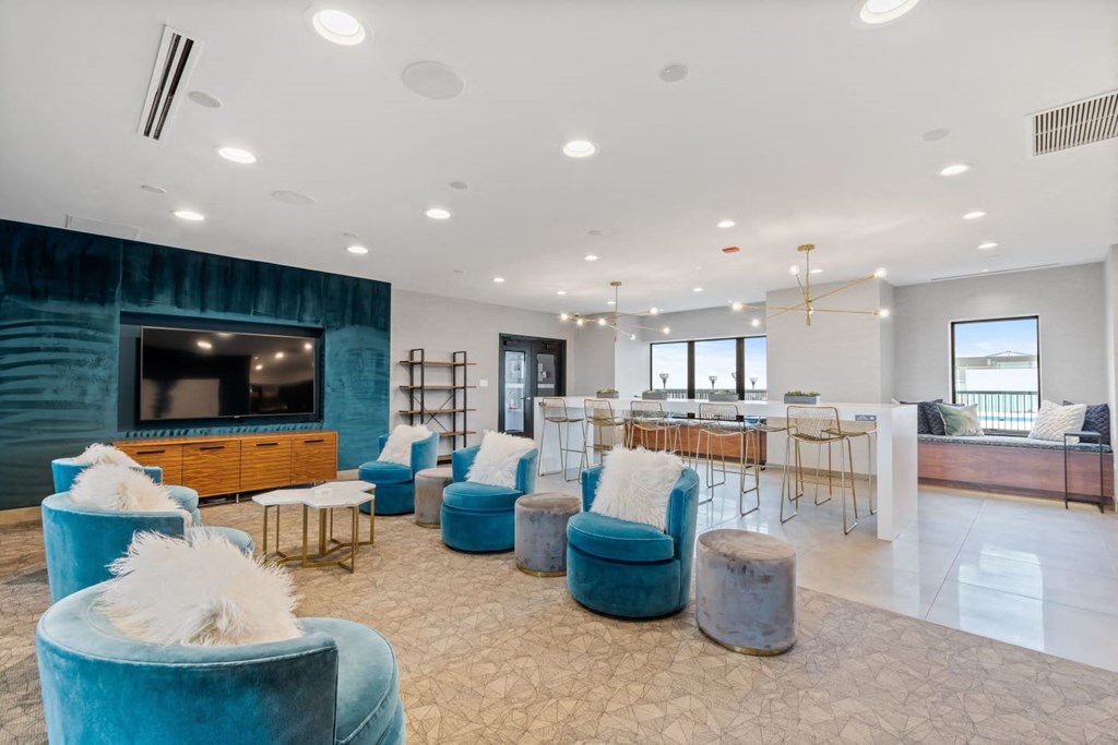 a living room with blue chairs and a bar and a television