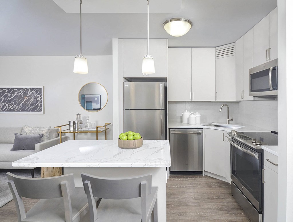 A modern kitchen with a marble table and stainless steel appliances.