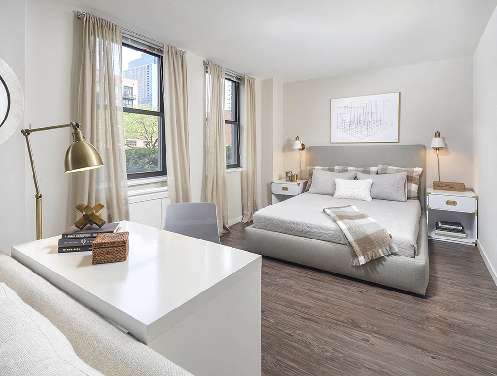A modern bedroom with a large bed and a white desk.