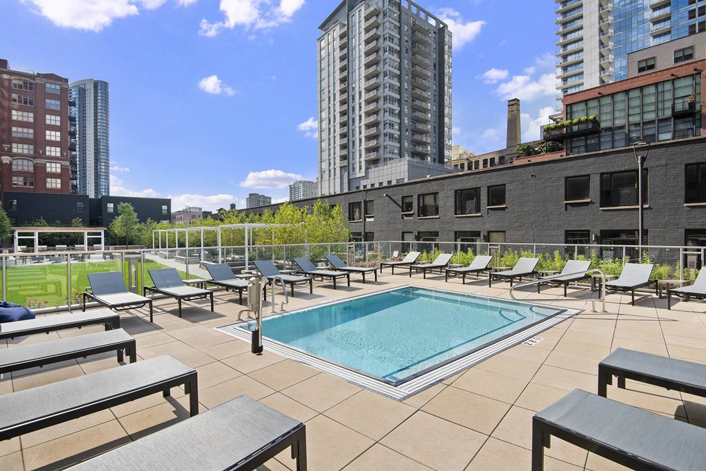 A pool surrounded by lounge chairs on a patio.