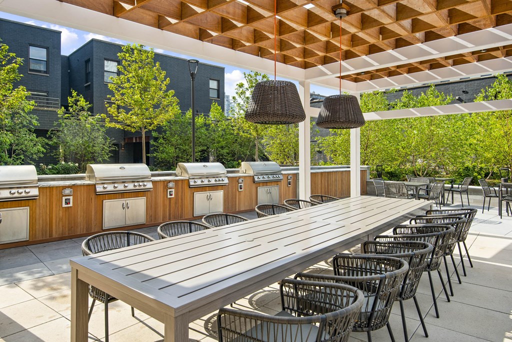 A wooden table with chairs under a wooden roof.