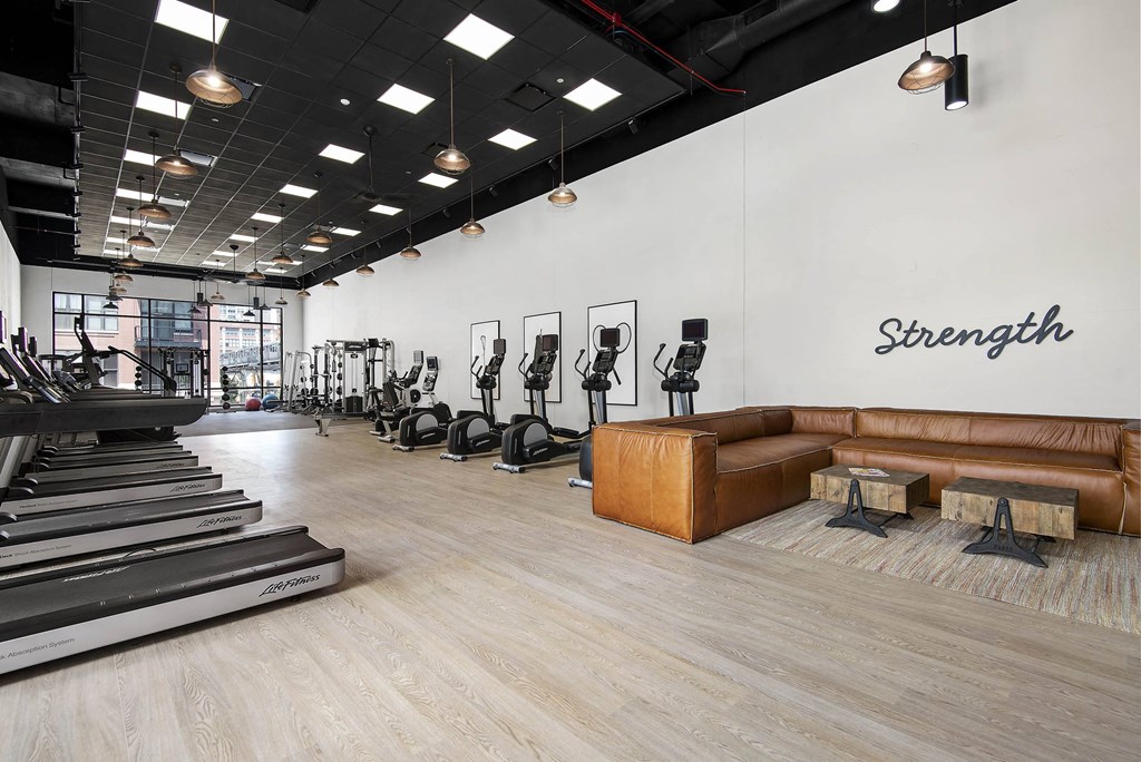 A gym with treadmills, weights, and a bench with the word "Strength" on the wall.