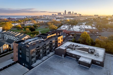 A cityscape is visible in the distance behind a parking lot and buildings.