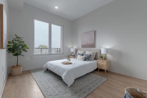 A bedroom with a large bed and a window overlooking a balcony.
