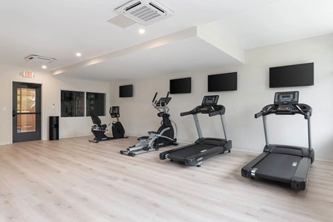 A gym with treadmills, elliptical machines, and other exercise equipment.