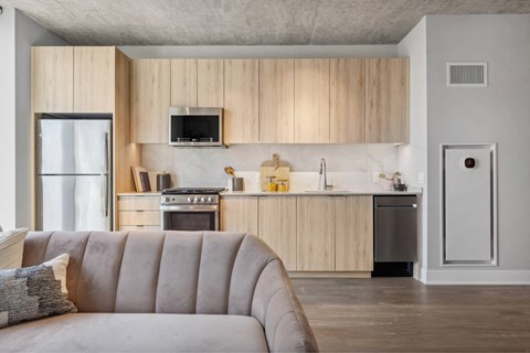 A modern kitchen with wooden cabinets and a grey sofa.