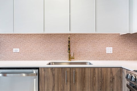 A kitchen with a stainless steel sink and wooden cabinets.