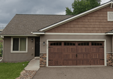 A house with a brown garage door and a grey roof.