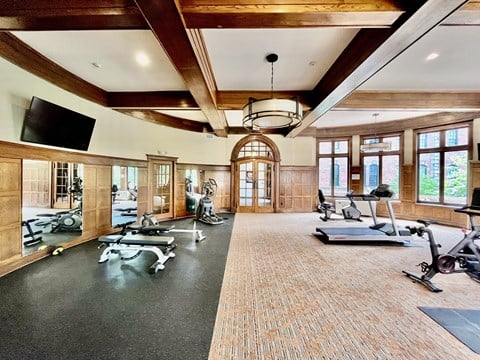 Fitness Center with treadmills and weights in a large room with windows and beamed ceilings