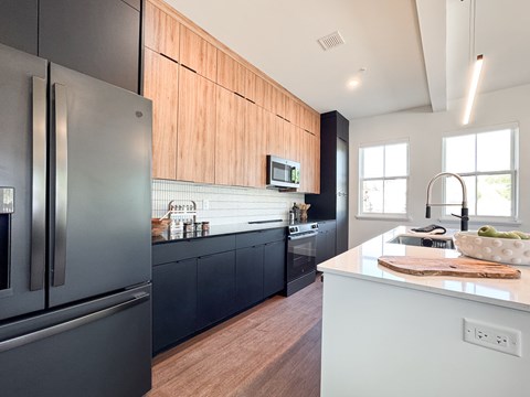 A modern kitchen with a black refrigerator and wooden cabinets.
