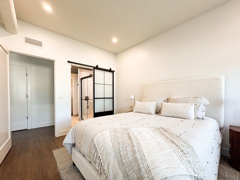 A bedroom with a large bed and a sliding glass door.