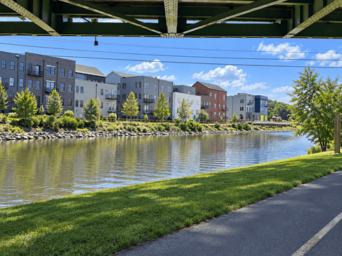 A river runs through a city with a bridge overhead and buildings on either side.