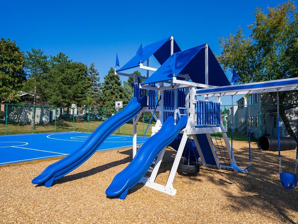 a swing set with a blue slide at a playground