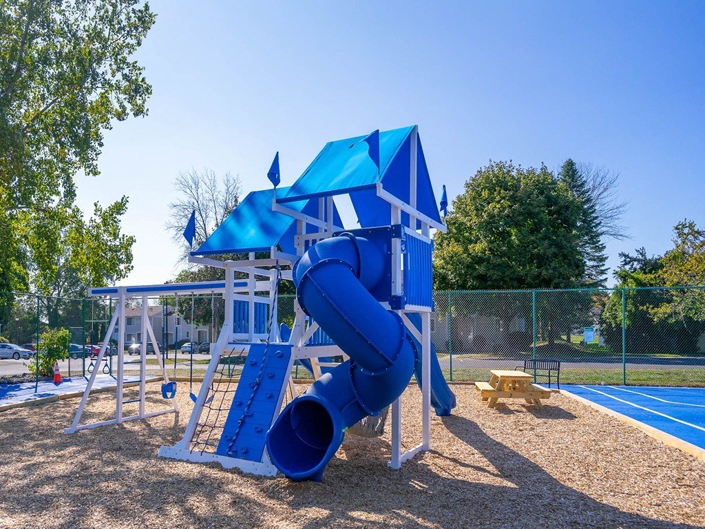 a playground with a blue playset and a slide