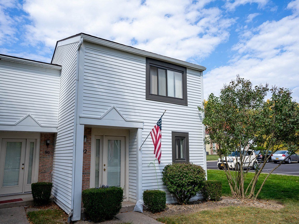 the exterior of a white building with an flag