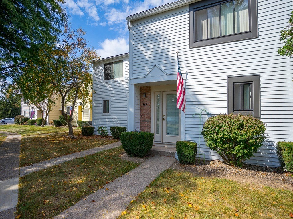 the front of a white house with an flag on the sidewalk