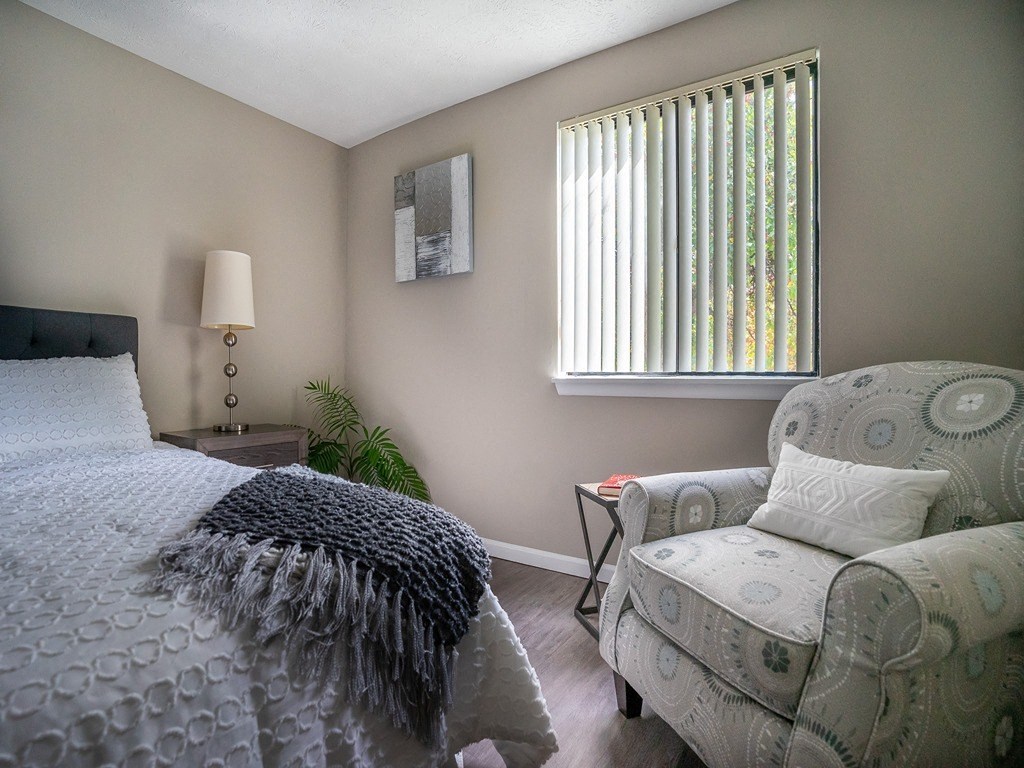 a bedroom with a bed and a chair and a window