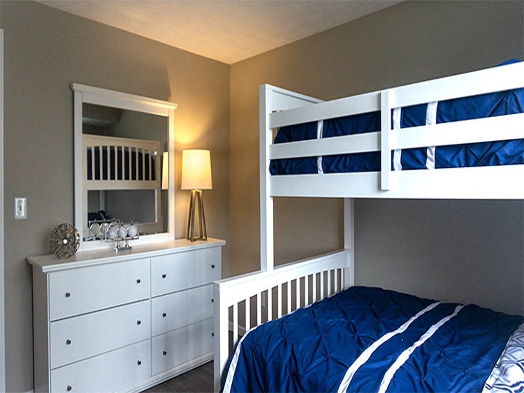 a bunk bed and dresser with a mirror in a bedroom