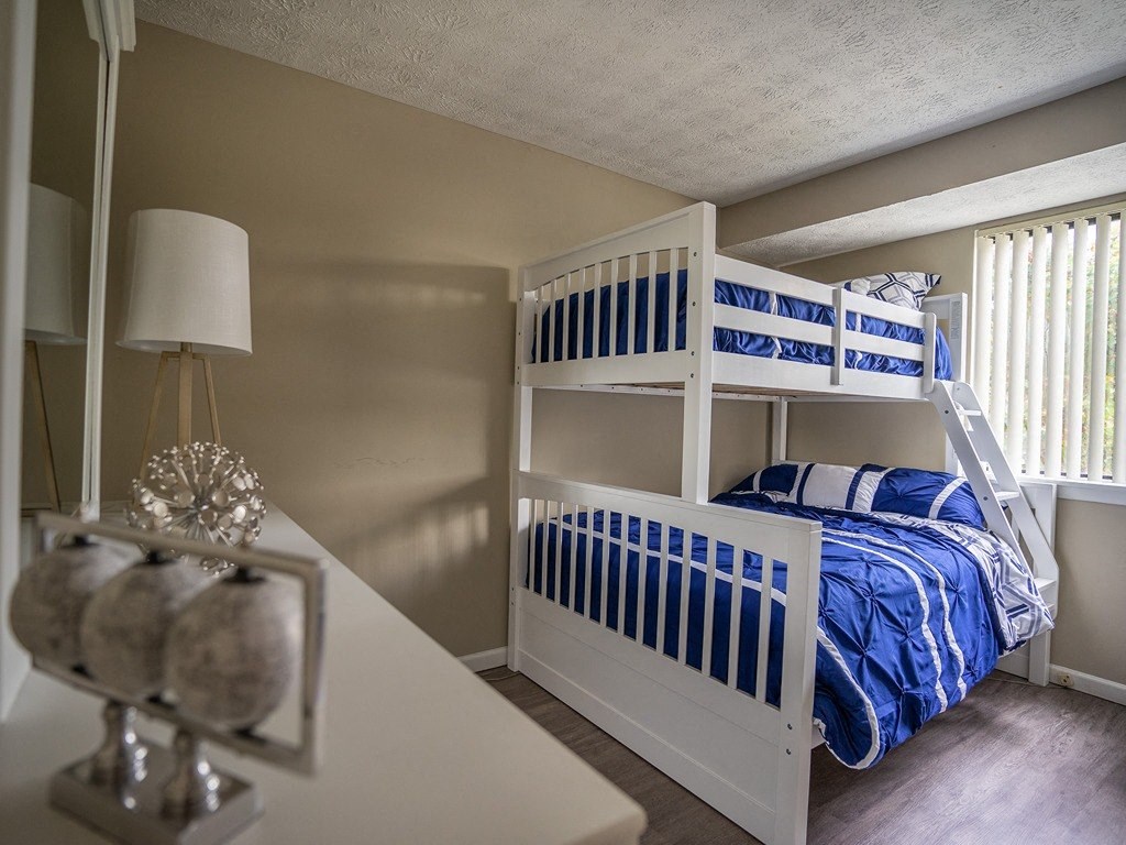 a bedroom with two bunk beds and a table and a lamp