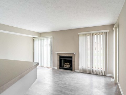 an empty living room with a fireplace and windows
