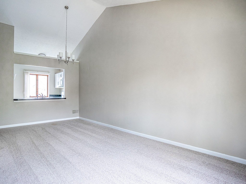 an empty living room with white walls and a window