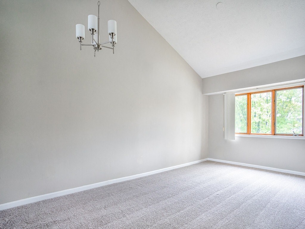an empty living room with a chandelier and a window