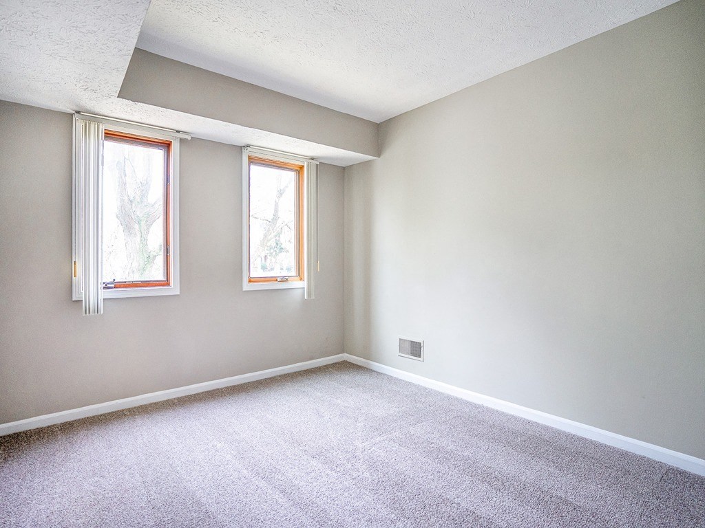 an empty living room with two windows and a carpet
