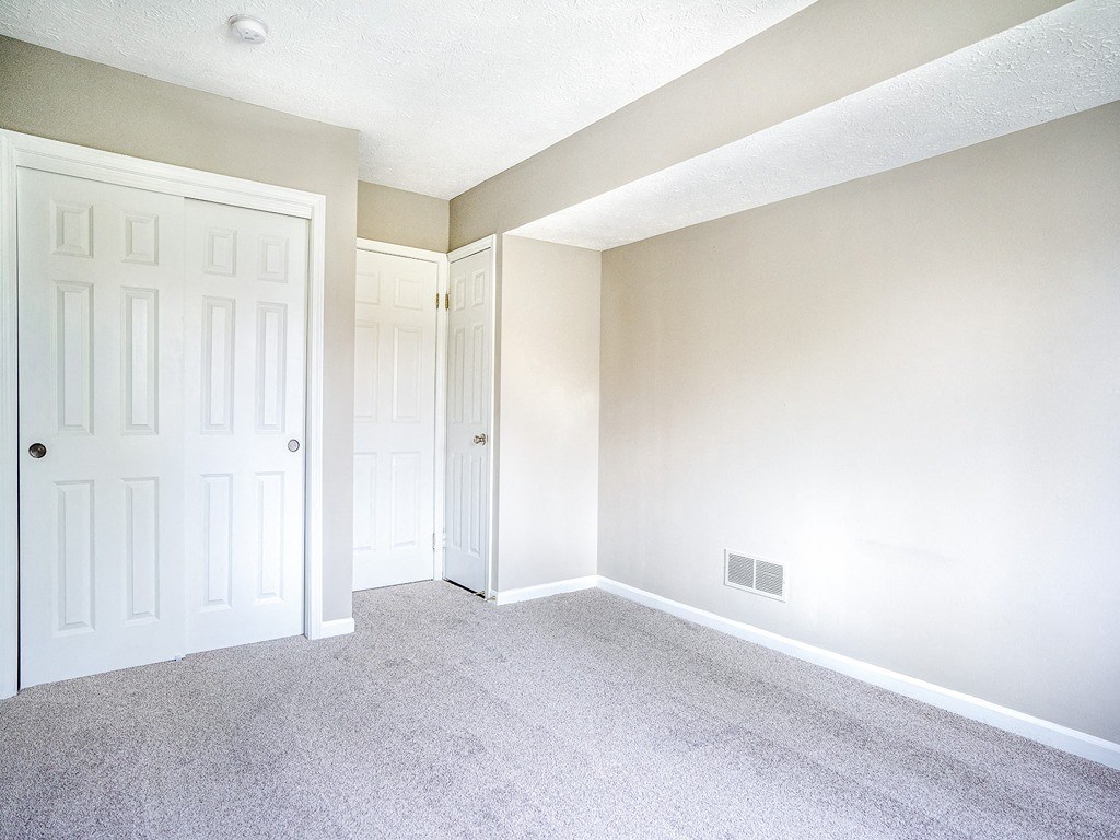 an empty room with white doors and a carpeted floor