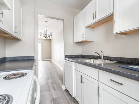 a kitchen with white cabinets and a white stove and sink