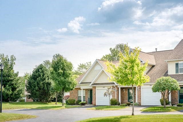 Exterior view of 2-story townhome & ranch end unit showing attached 1-car garages & guest parking