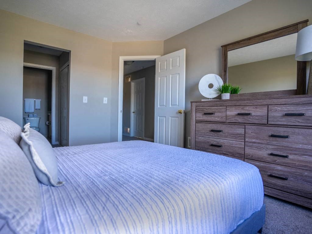 Interior view of carpeted bedroom showing doors to jack-n-jill closet/bathroom & hallway