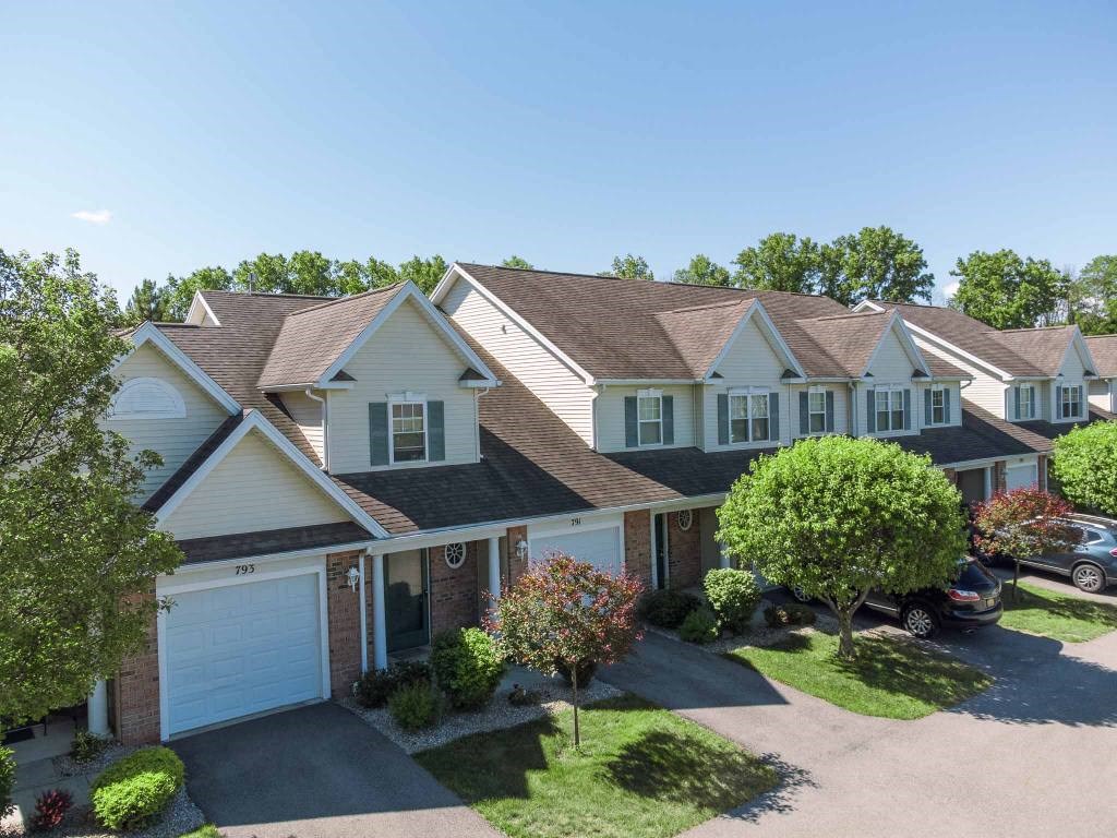 Exterior view of Webster Woods townhomes showing multiple 2-story townhouse entrances with attached 1-car garages and driveways