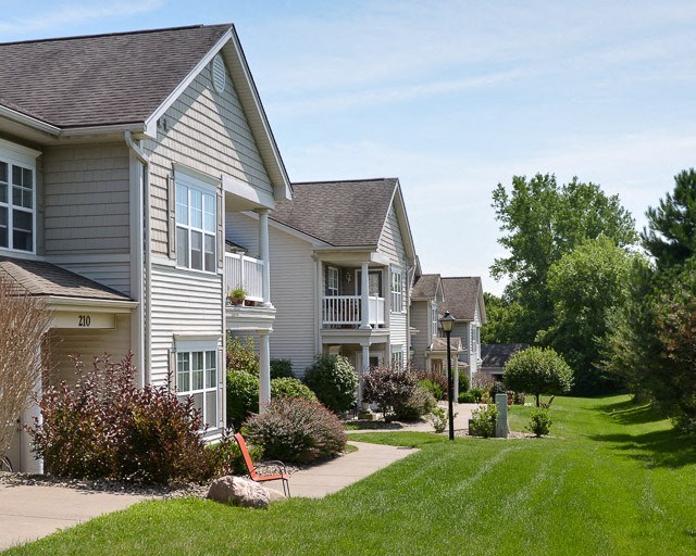 a row of houses with a lawn and a sidewalk