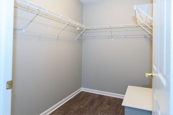 a walk in closet with white shelves and a door