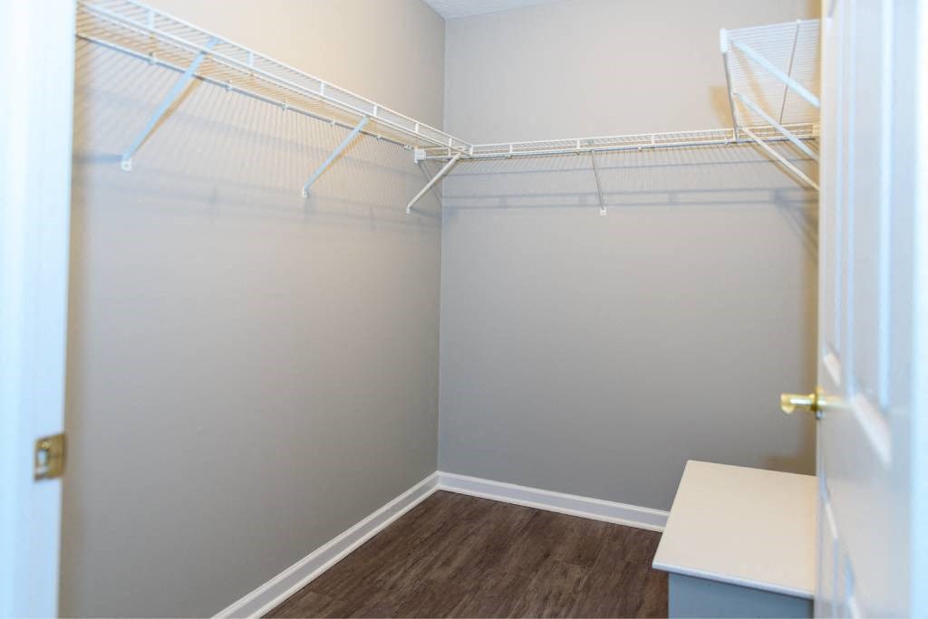 a walk in closet with white shelves and a door