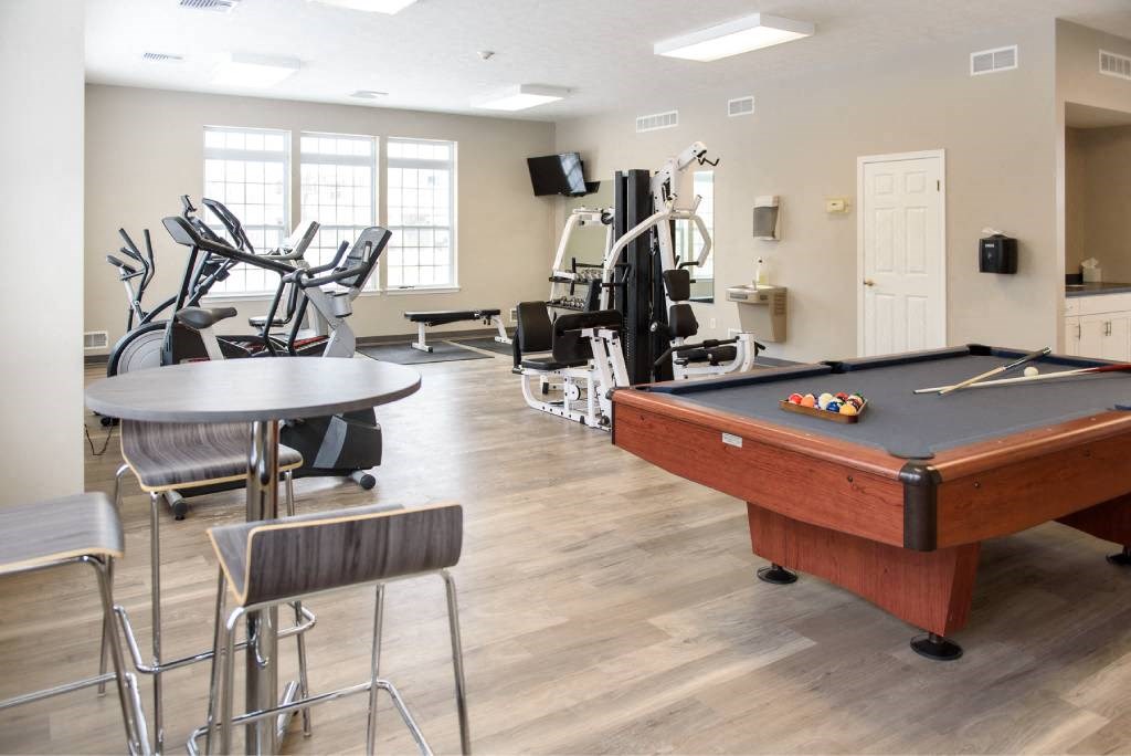 a games room with a pool table and gym equipment