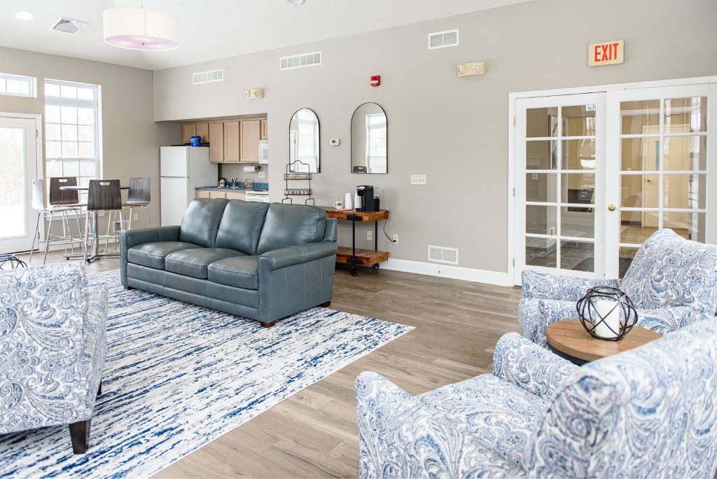 a living room and kitchen with a couch and chairs