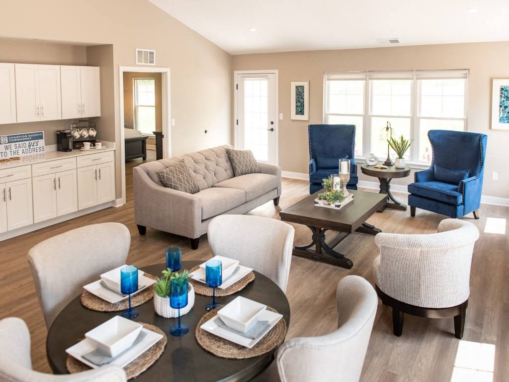 Interior of Champion Reserve Townhome Great Room showing living area, dining area, coffee bar, and doors to private patio and primary bedroom.
