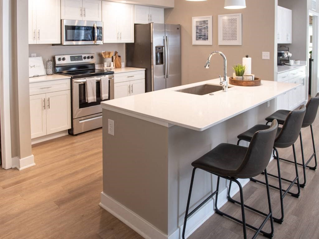 Interior of Champion Reserve Townhome  with view of well equipped kitchen with stainless steel appliances, quartz countertops, and breakfast bar/kitchen island.