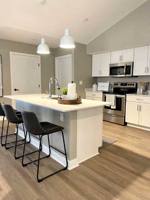 a kitchen with a center island with three chairs