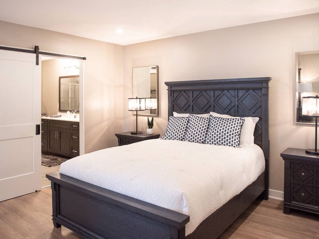 Interior of Champion Reserve Townhome primary bedroom with ensuite bathroom and faux wood flooring.