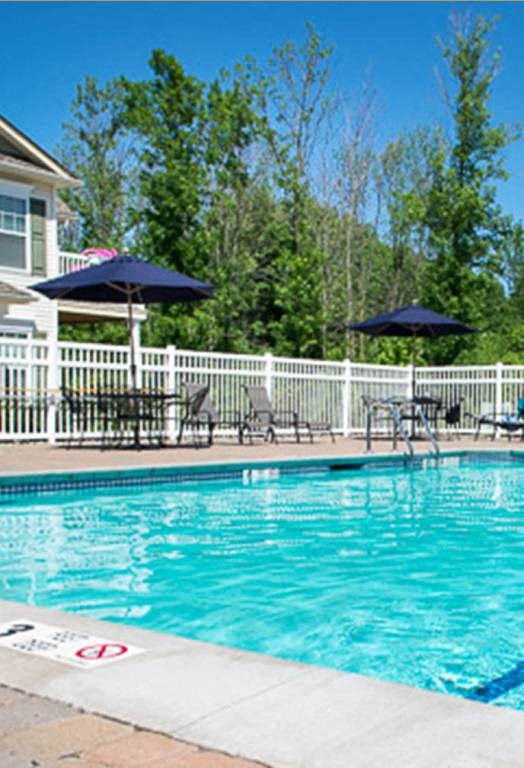 Outdoor swimming pool with large pool deck, tables, and chaise longues