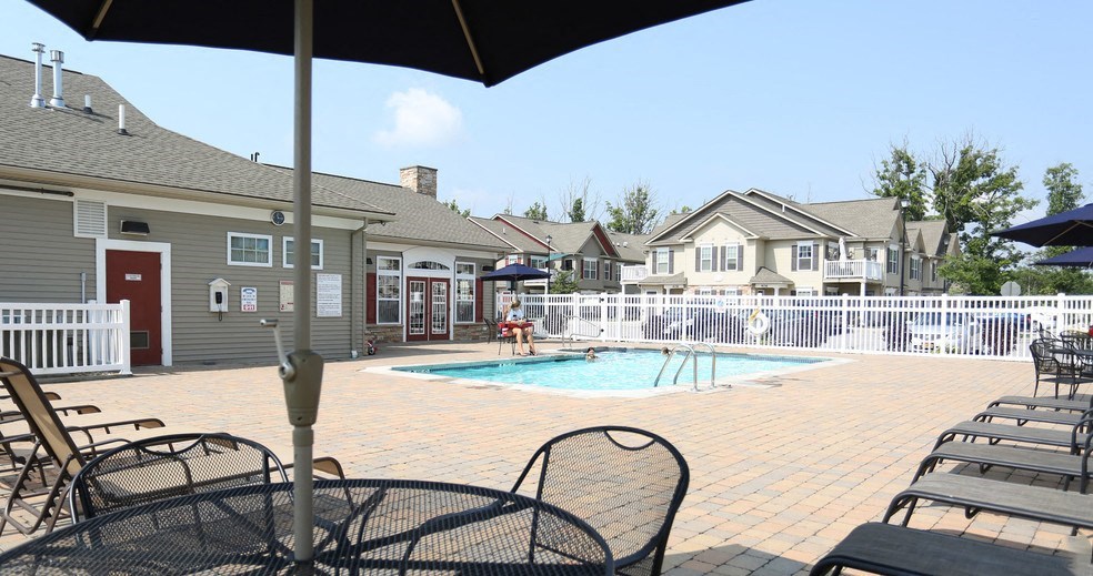 Outdoor swimming pool with large pool deck, tables, and chaise longues